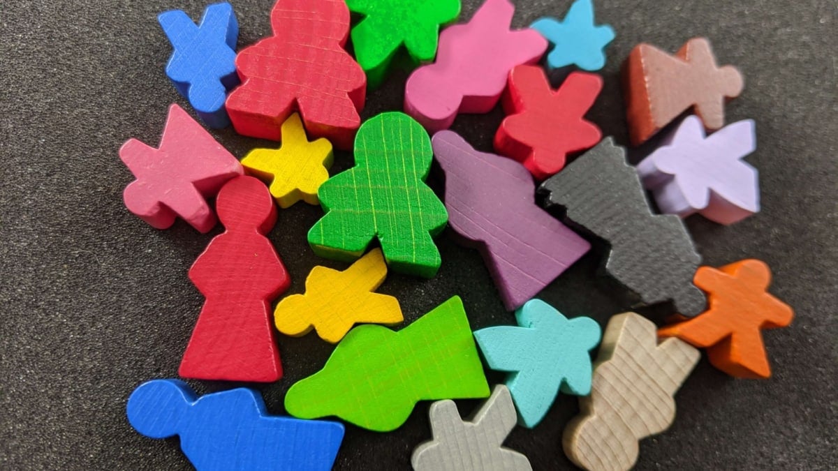 A screenshot of multiple meeples of different sizes, shapes, and colors on a black background.